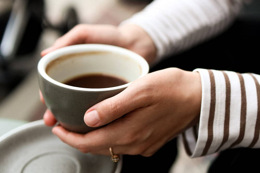 A pair of hands cupped around a warm bowl of coffee